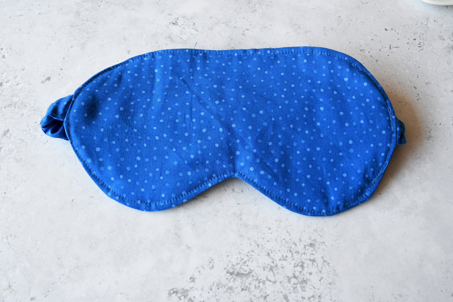 Nahaufnahme des blauen Baumwollstoffes mit zeitlosen blauen Punkten der Schlafmaske Dottie Blue