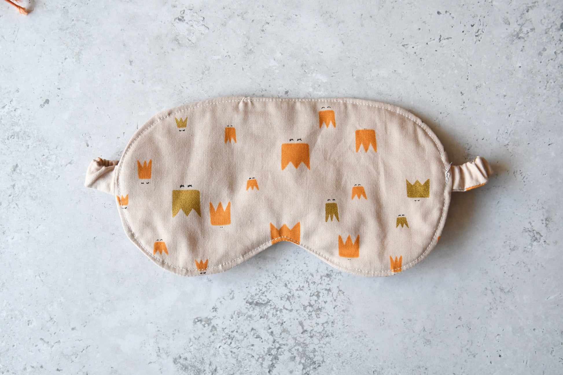 Nahaufnahme des altrosafarbenen Baumwollstoffes mit kleinen, goldenen Kronen-Motiven