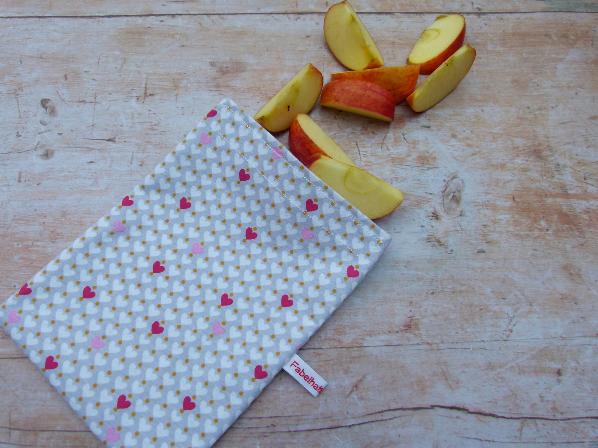 Handgenähter, nachhaltiger Snackbag von Fabelhaftewerkstatt aus lebensmittelechtem Stoff, geöffnet und befüllt mit Apfelscheiben auf einem Küchentisch.