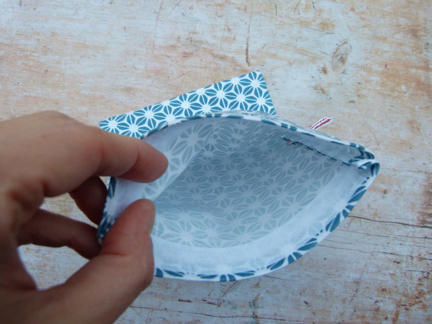 Detailansicht eines handgemachten Snackbags, bei dem eine Hand das saubere, weiße Innere aus zertifiziertem, lebensmittelechtem und wasserabweisendem PUL-Stoff zeigt.