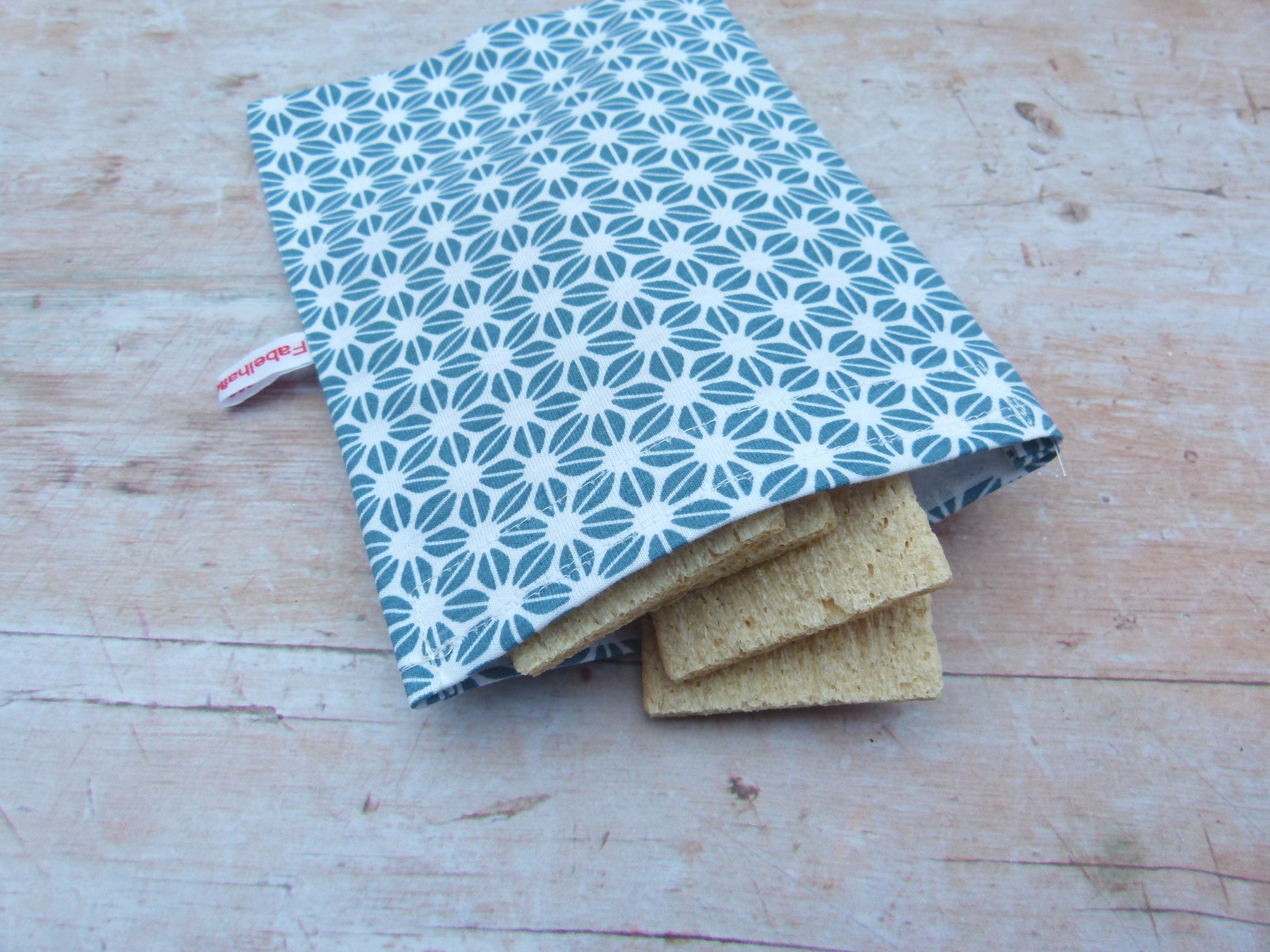 Handgenähter, nachhaltiger Snackbag von Fabelhaftewerkstatt aus lebensmittelechtem Stoff, geöffnet und befüllt mit Knäckebroten auf einem Küchentisch.