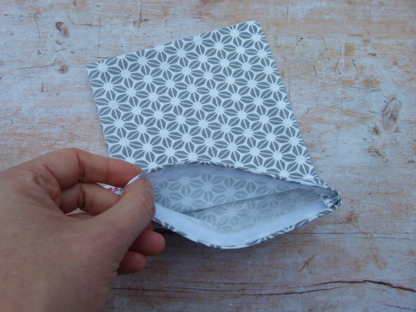 Detailansicht eines handgemachten Snackbags, bei dem eine Hand das saubere, weiße Innere aus zertifiziertem, lebensmittelechtem und wasserabweisendem PUL-Stoff zeigt.
