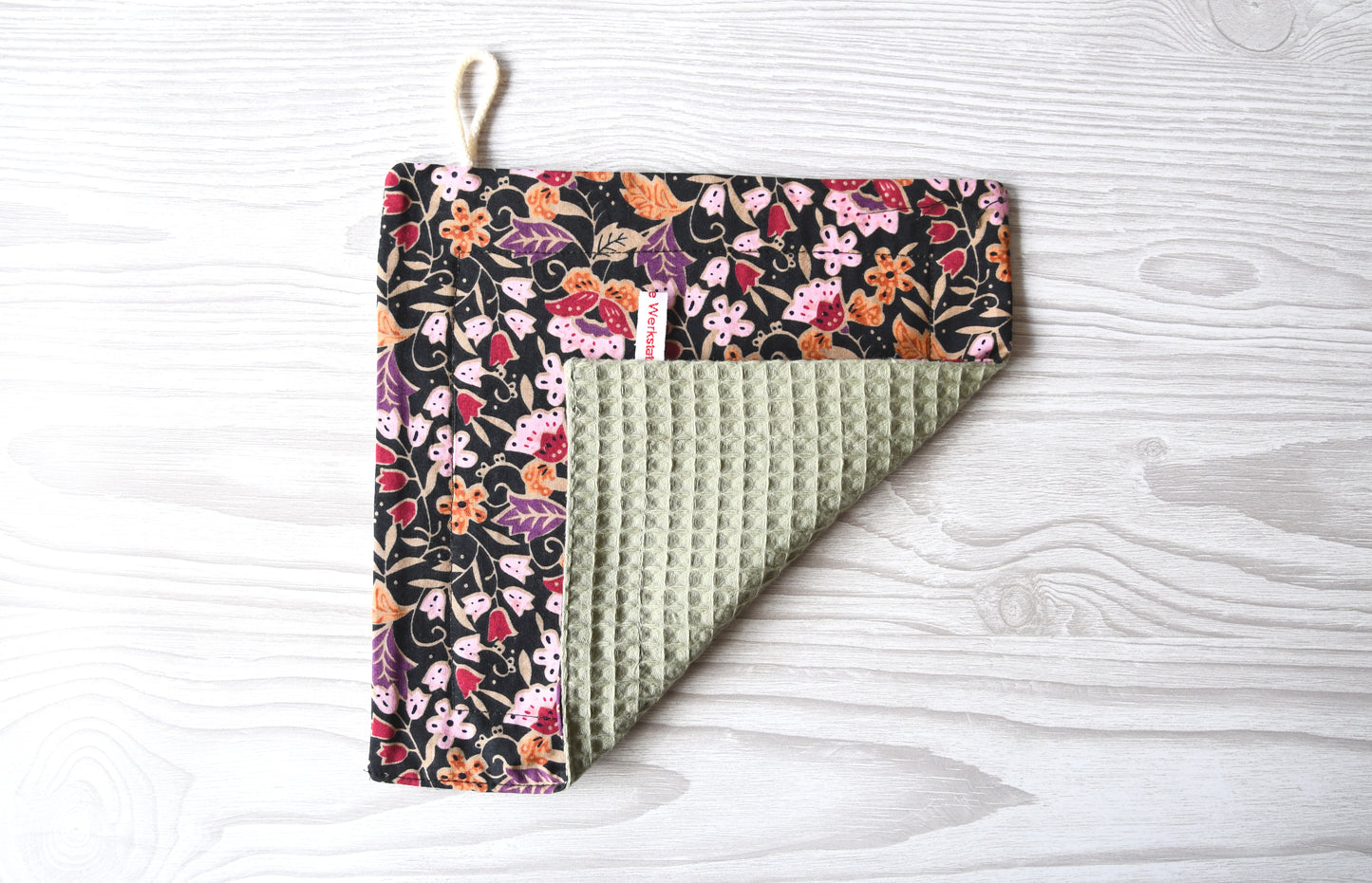 Elegantes, handgenähtes Spültuch mit einem farbenfrohen Blumenmuster auf einem dunklen, kontrastreichen Hintergrund von Fabelhaftewerkstatt.