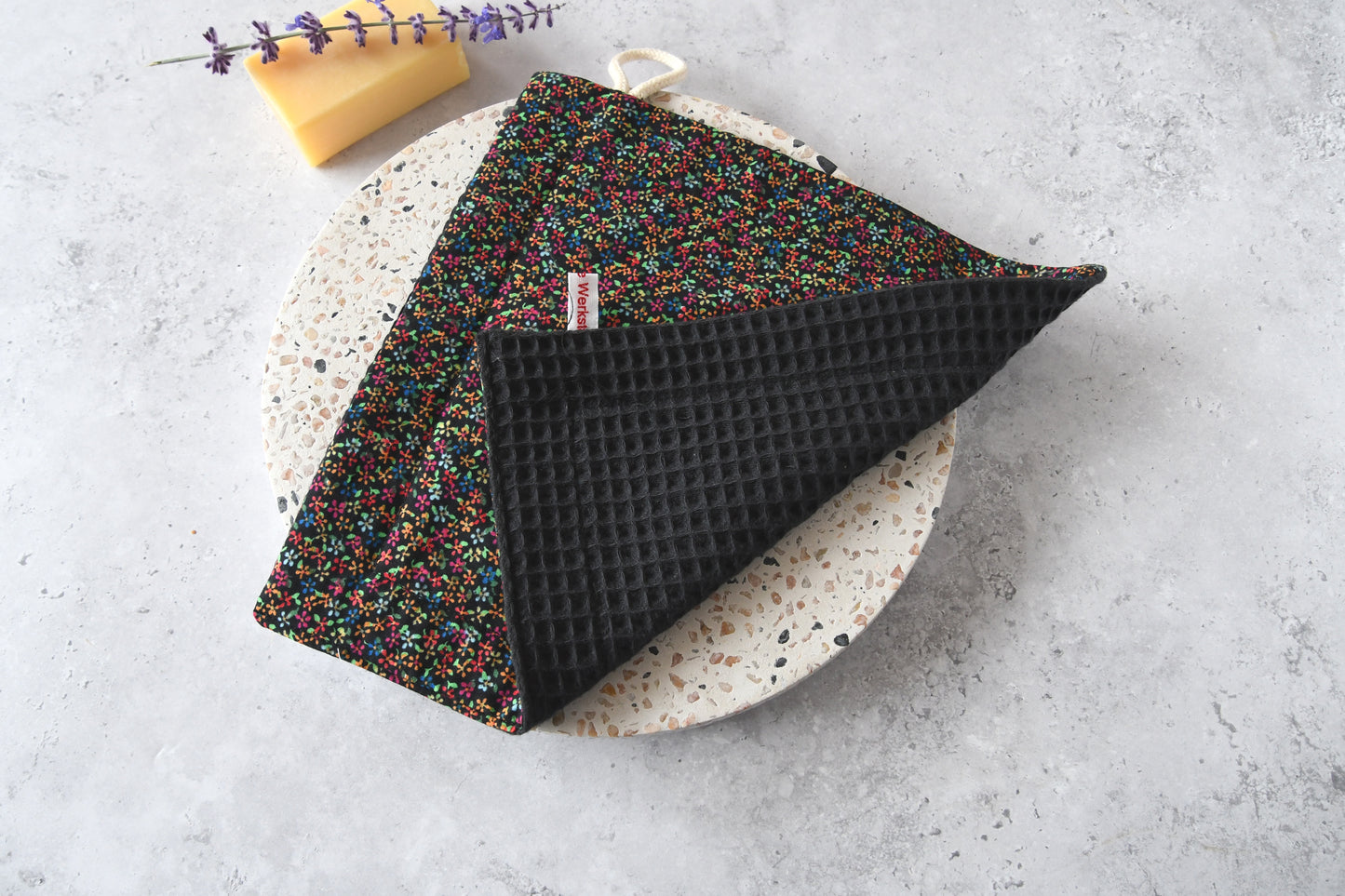 Nahaufnahme des Spültuchs mit umgeklappter Ecke: Vorderseite mit Motiv und saugstarke Rückseite aus Waffelpique.